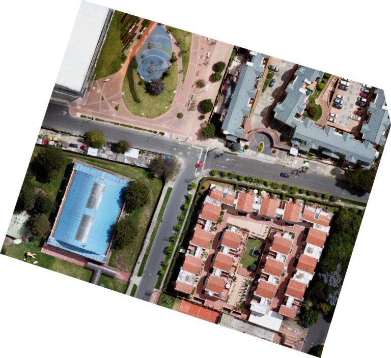 Ortofotografía de un conjunto residencial tomada desde un dron, que muestra una vista aérea detallada del complejo y sus alrededores. La imagen ofrece una vista clara de la disposición de los edificios, las áreas verdes y los servicios disponibles para los residentes.